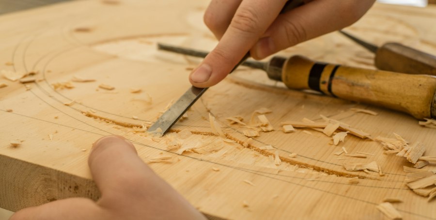 Hands carving wood with a chisel